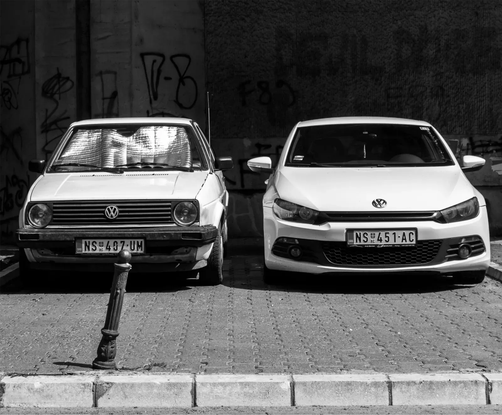 Foto en blanco y negro de un Volkswagen Golf antiguo estacionado junto a un Volkswagen moderno