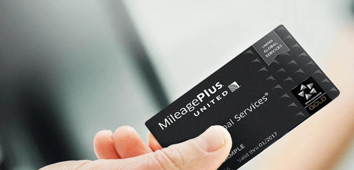 Mano que sostiene la tarjeta negra MileagePlus Global Services de United Airlines con el sello Star Alliance Gold